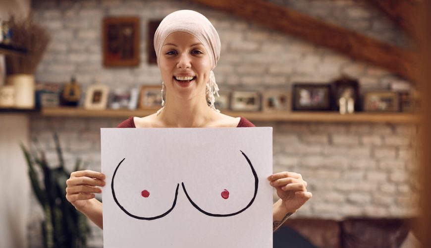 Mujer joven con cáncer sostiene un dibujo de senos