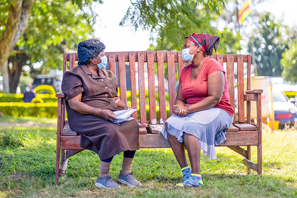 Dos mujeres hablando en un banco de la amistad para mejorar la salud mental